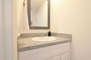 Un bagno con piano in granito, lavandino bianco e specchio.