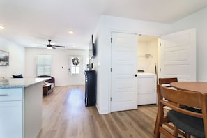 Una cucina moderna con mobili bianchi, un tavolo da pranzo in legno e una ventola a soffitto.