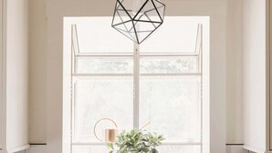 Une cuisine dotée d’un évier moderne, d’un luminaire géométrique suspendu et d’une fenêtre donnant sur un paysage verdoyant.