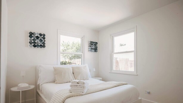 A bedroom with a bed, two bedside tables, and two wall-mounted circular art pieces. - Denver Basecamp | Workspace | Pet-Friendly 30+ (Denver)