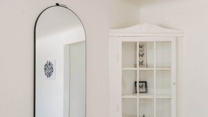 A room with a white cabinet with glass doors, a black-framed mirror, and a small framed picture on the cabinet. - Denver Basecamp | Workspace | Pet-Friendly 30+ (Denver)