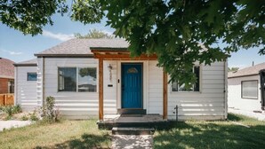 A single-story house with a blue front door, a small porch, and a clear sky. - Denver Basecamp | Workspace | Pet-Friendly 30+ (Denver)