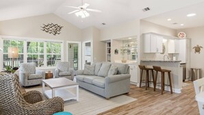 A spacious living area with a sofa, chairs, a coffee table, a kitchen with bar stools, and a ceiling fan. - Golf View Villa w/ Optional Golf Cart | 3BR/3BA | Near Beach & Pool | Port Royal (Hilton Head Island)