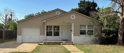 A single-story house with a garage, a front porch, and a small front yard.
