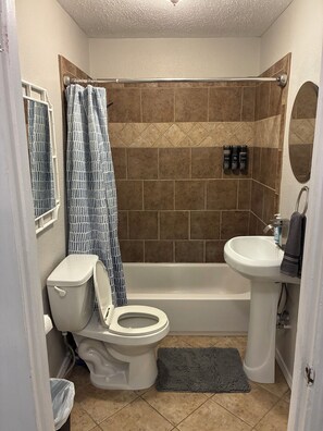 A bathroom with a toilet, shower, and sink. - Central 2BR Home with AC: Near Texas Tech & Covenant Medical Center (Lubbock)