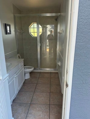A bathroom with a shower, toilet, and vanity. - Spacious 4-bedroom house in delightful Cape Coral with AC (Cape Coral)