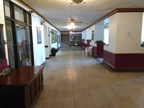 A hallway with a wooden bench, potted plants, and a ceiling fan.