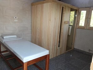A room with a wooden wardrobe, a bed with a white mattress, and a window with a view of greenery. - ABU Guest House (Aswan)