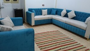 Ein Wohnzimmer mit einem blauen Modulsessel, einem kleinen Tisch und einem Streifenmuster-Teppich.