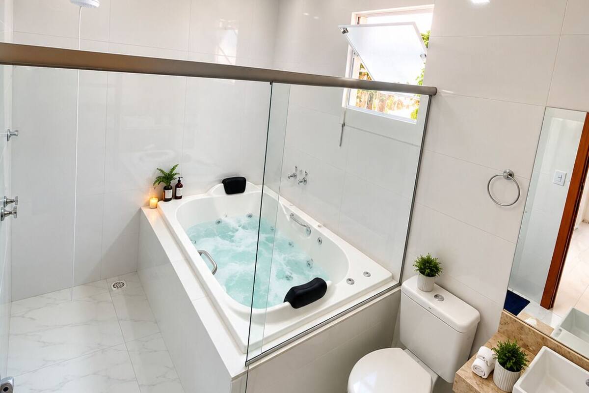 Un baño moderno con cabina de ducha de vidrio, bañera independiente, inodoro y lavamanos.