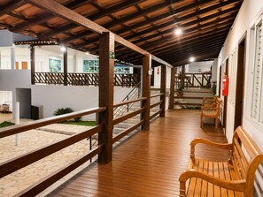 A covered outdoor area with wooden railings, a wooden bench, and a staircase leading to an upper level. - Pousada Escarpas  (Capitólio)