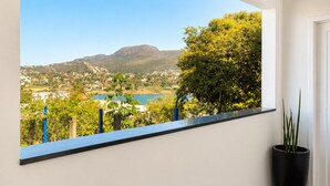 Quarto com uma grande janela que oferece vista para uma paisagem deslumbrante, um vaso de planta e piso de madeira.