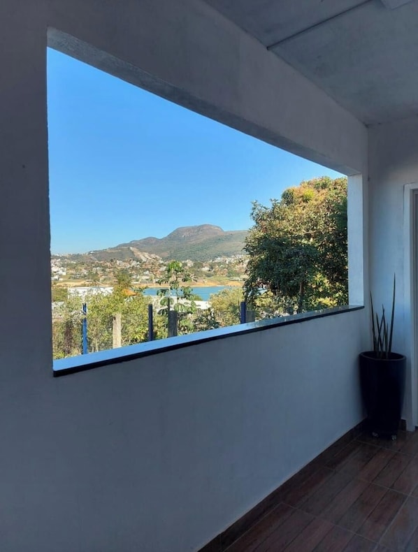 Una habitación con un ventanal que ofrece vistas a un lago, colinas y un árbol.