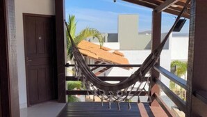Uma área externa coberta com uma rede, deck de madeira e uma porta.