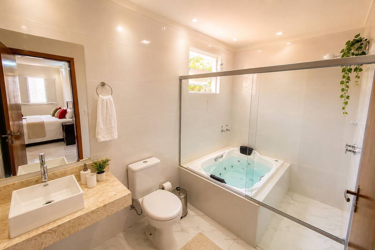 Un baño moderno con ducha de vidrio, una bañera grande, un inodoro y un lavamanos.