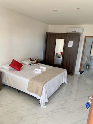 A hotel room with a bed, a wardrobe, a mirror, and a bathroom visible through an open door. - Pousada Escarpas  (Capitólio)