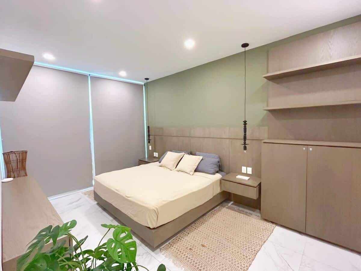 A modern bedroom with a bed, bedside tables, a wardrobe, and a plant.