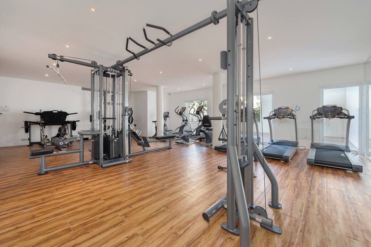 Une salle de sport équipée de divers appareils d’exercice, notamment un support à squats, des tapis de course et des appareils de musculation.