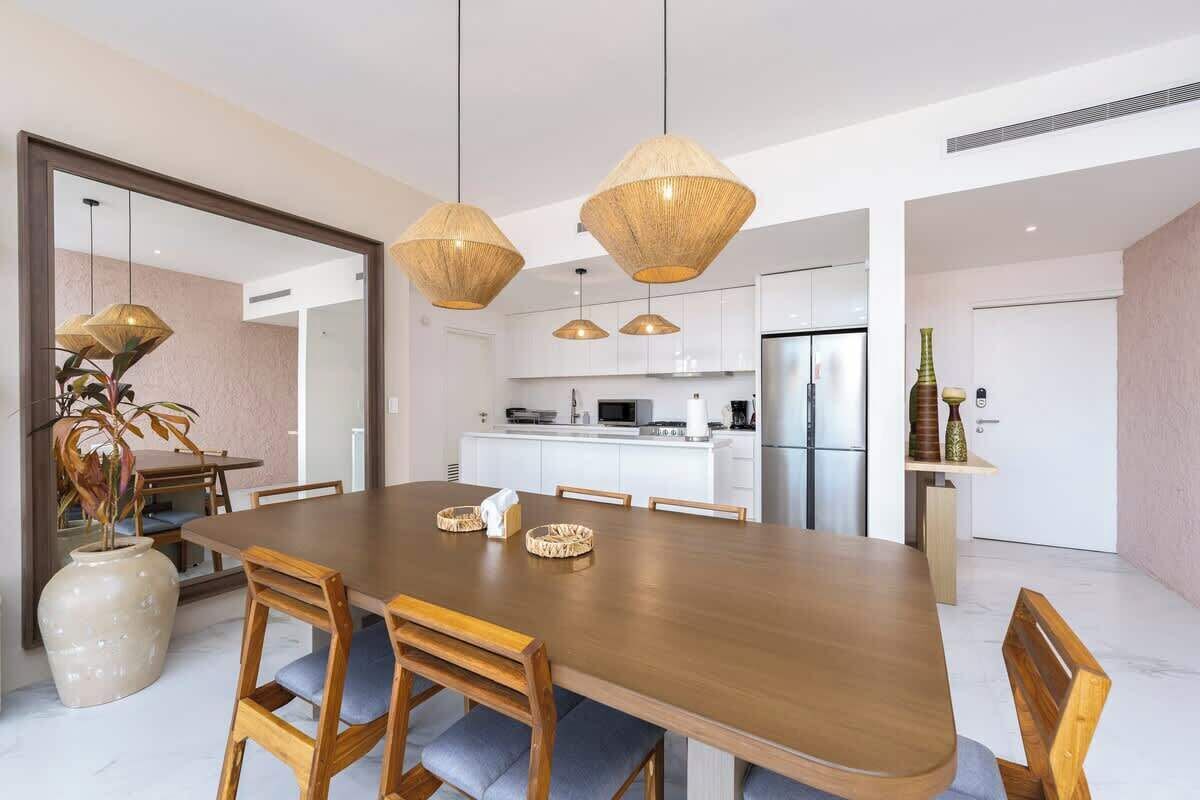 A modern dining area with a wooden table, chairs, and hanging pendant lights.