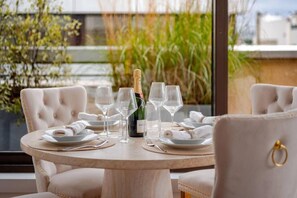 A round dining table with six wine glasses, a bottle of champagne, and folded white napkins. - Elysee's Residence / Luxury 1 Bed Serviced Apartment (Paris)