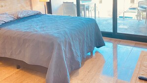 Un dormitorio con una cama grande, una mesita de noche, una lámpara y vistas al exterior.