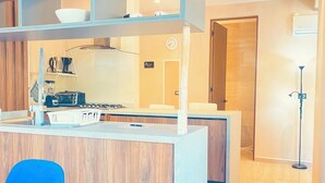 Una cocina moderna con una isla central, muebles de madera y un comedor con sillas azules.