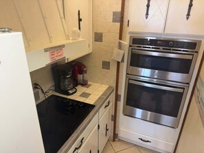 Une cuisine équipée d’une cuisinière, d’une machine à café et de deux fours.
