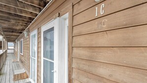 A wooden building with a covered porch, a door with glass panels, and the number 'IC' on the wall. - Sherwood 1C (Ocean City)