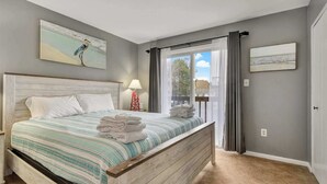 A bedroom with a bed, a nightstand, a lamp, and artwork on the walls. - Sherwood 1C (Ocean City)