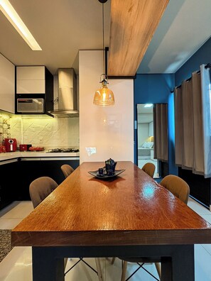 Eine moderne Küche mit einem Holztisch, einer Pendelleuchte und einer Mikrowelle.