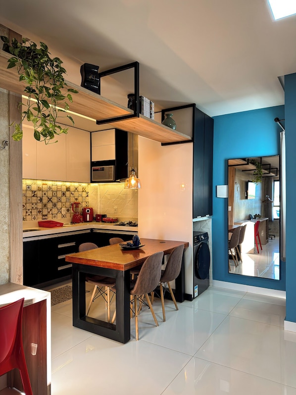 Una cocina moderna con isla de madera, armarios negros y salpicadero de azulejos.