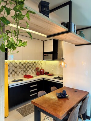 Een moderne keuken met een centraal eiland, zwarte kastjes en een houten eettafel.