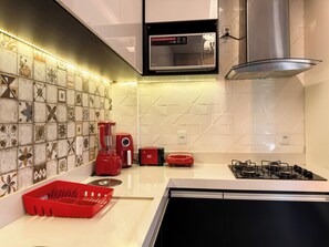 A modern kitchen with a microwave, gas stove, and a red coffee maker.