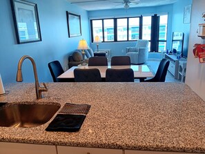 A kitchen with granite countertops, a sink, and a dining area with chairs and a table. - Beautiful Brigantine Beach Beach Block Condo--2 Bed--2 Bath (Brigantine)