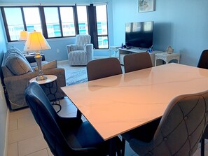 Un salon comprenant une table à manger, des chaises, un canapé, un téléviseur et une lampe.