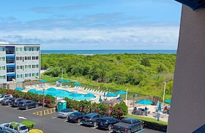 Un hotel con piscina, varias sillas de descanso y vista al océano.