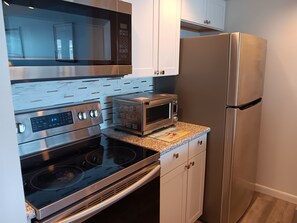 A kitchen with stainless steel appliances including a microwave, oven, and refrigerator. - Beautiful Brigantine Beach Beach Block Condo--2 Bed--2 Bath (Brigantine)