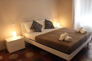 A bed with a brown bedspread, two patterned pillows, and two white pillows. There are two bedside tables with lamps, and towels are folded on the bed. - VATICANO ROMA GUESTHOUSE (Rome)