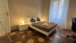 A bedroom with a bed, nightstands, a chair, and a window with curtains. - VATICANO ROMA GUESTHOUSE (Rome)