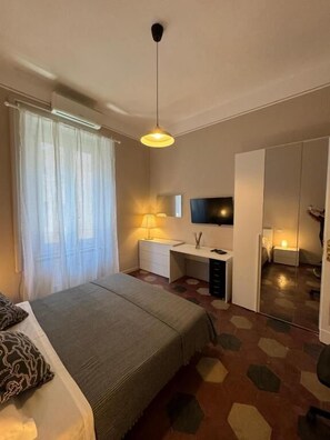 A bedroom with a bed, a desk, a chair, a TV, and a wardrobe. - VATICANO ROMA GUESTHOUSE (Roma)