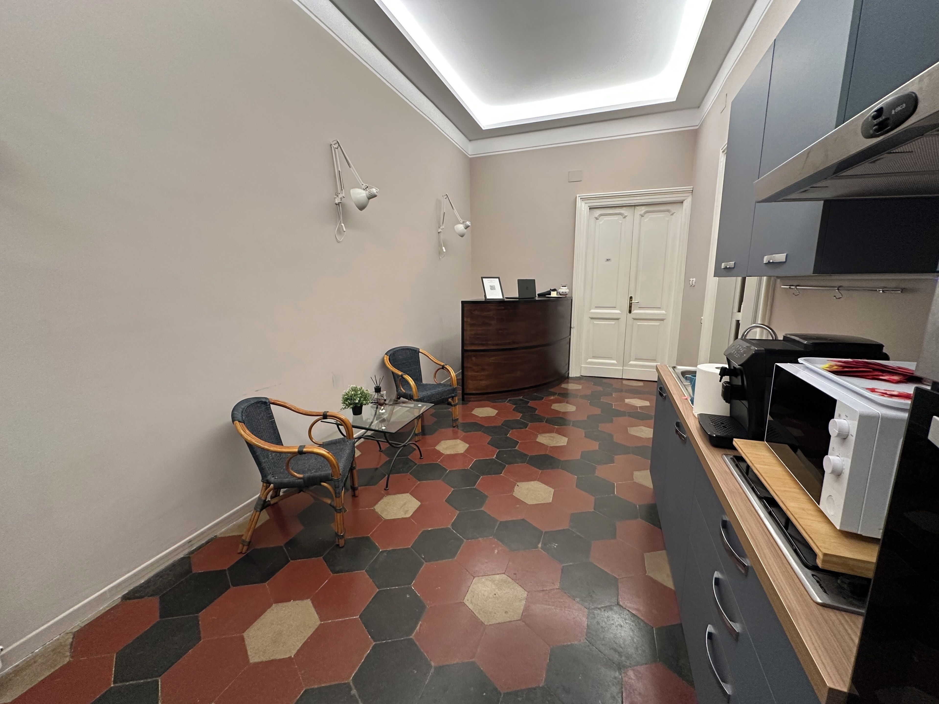 A compact kitchen with a microwave, toaster, and a small dining area with two chairs and a table.