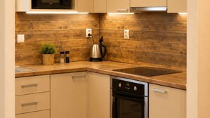 A compact kitchen with a microwave, oven, and built-in cabinets. - Apartment Pred Polom (Trenčín)