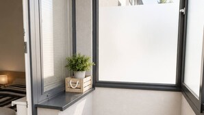 A corner room with a window, a small plant, a wicker basket, and a bed. - Apartment Pred Polom (Trenčín)