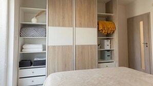 A bedroom with a bed, a wardrobe with multiple shelves, and a door. - Apartment Pred Polom (Trenčín)