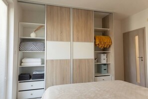 A bedroom with a bed, a wardrobe with multiple shelves, and a door.
