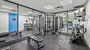 Ett gym med träningsredskap, en bänk och en spegel.
