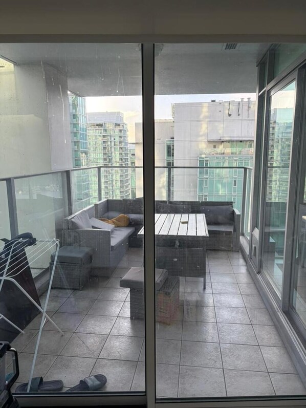 A balcony with a seating area, a table, and a drying rack.