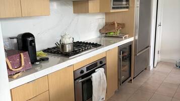 Une cuisine moderne avec des meubles en bois, une cuisinière à gaz, un four à micro-ondes et un réfrigérateur en acier inoxydable.