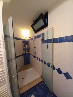 Ein kleines Badezimmer mit Dusche, Spiegel und einem darüber montierten Fernseher.