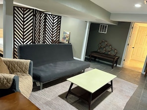 A living room with a sofa, a small table, a patterned rug, a decorative bench, and a wall with a chevron pattern. - Private office space plus studio vibe bedroom/ living room. Full kitchen W&Dryer (Mableton)